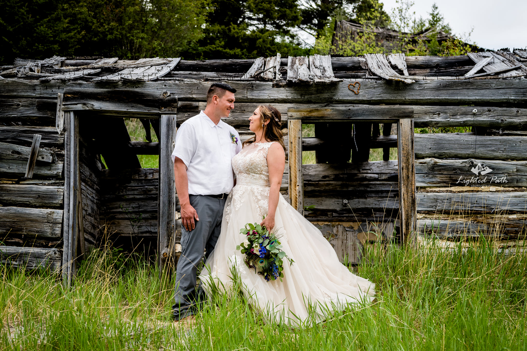 bride and groom in front of old wooden barn