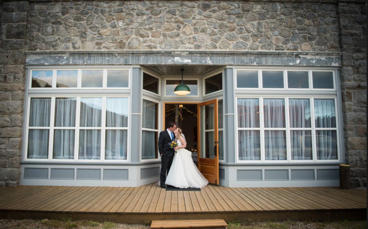 bride and groom kissing in front of large windows of Historic Marysville General Store