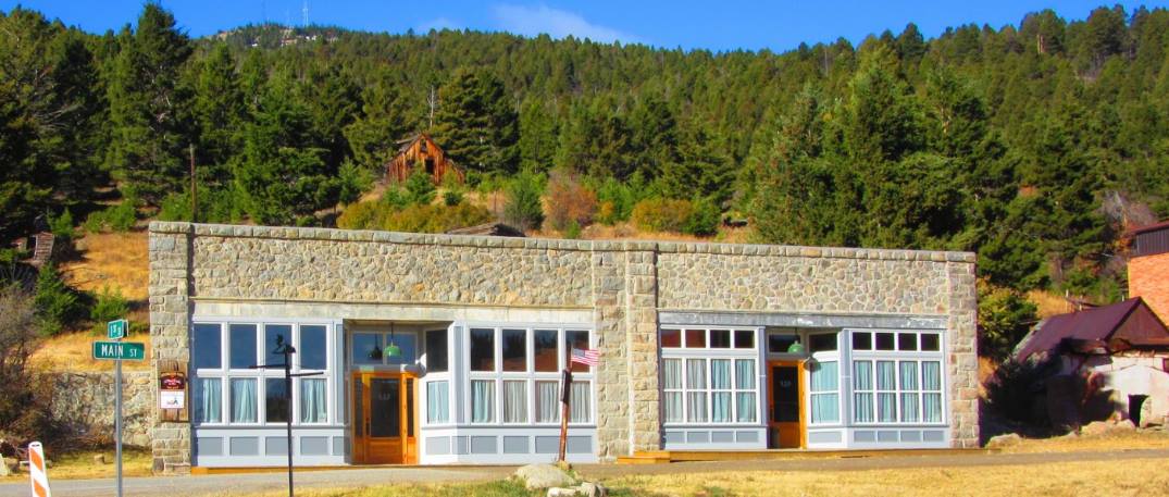 stone exterior of Historic Marysville General Store with large windows with mountains in the background