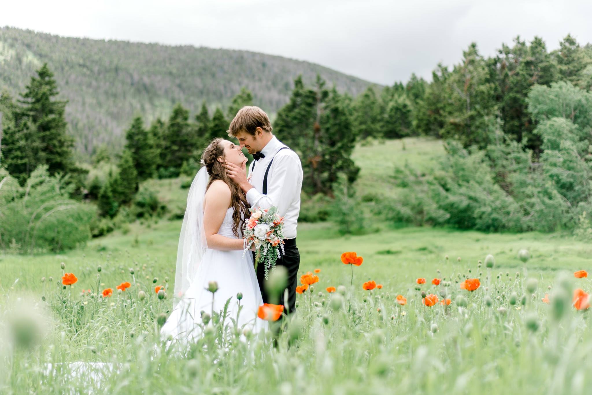 bride and groom in Montana countryside surrounded by poppies and green trees