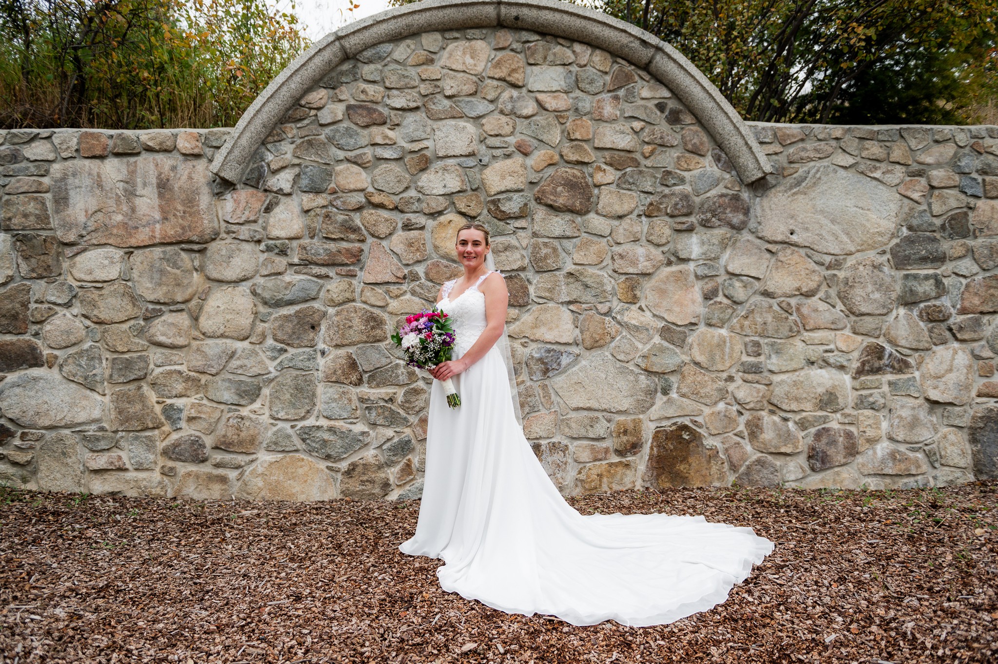 bride standing in front of stone wall