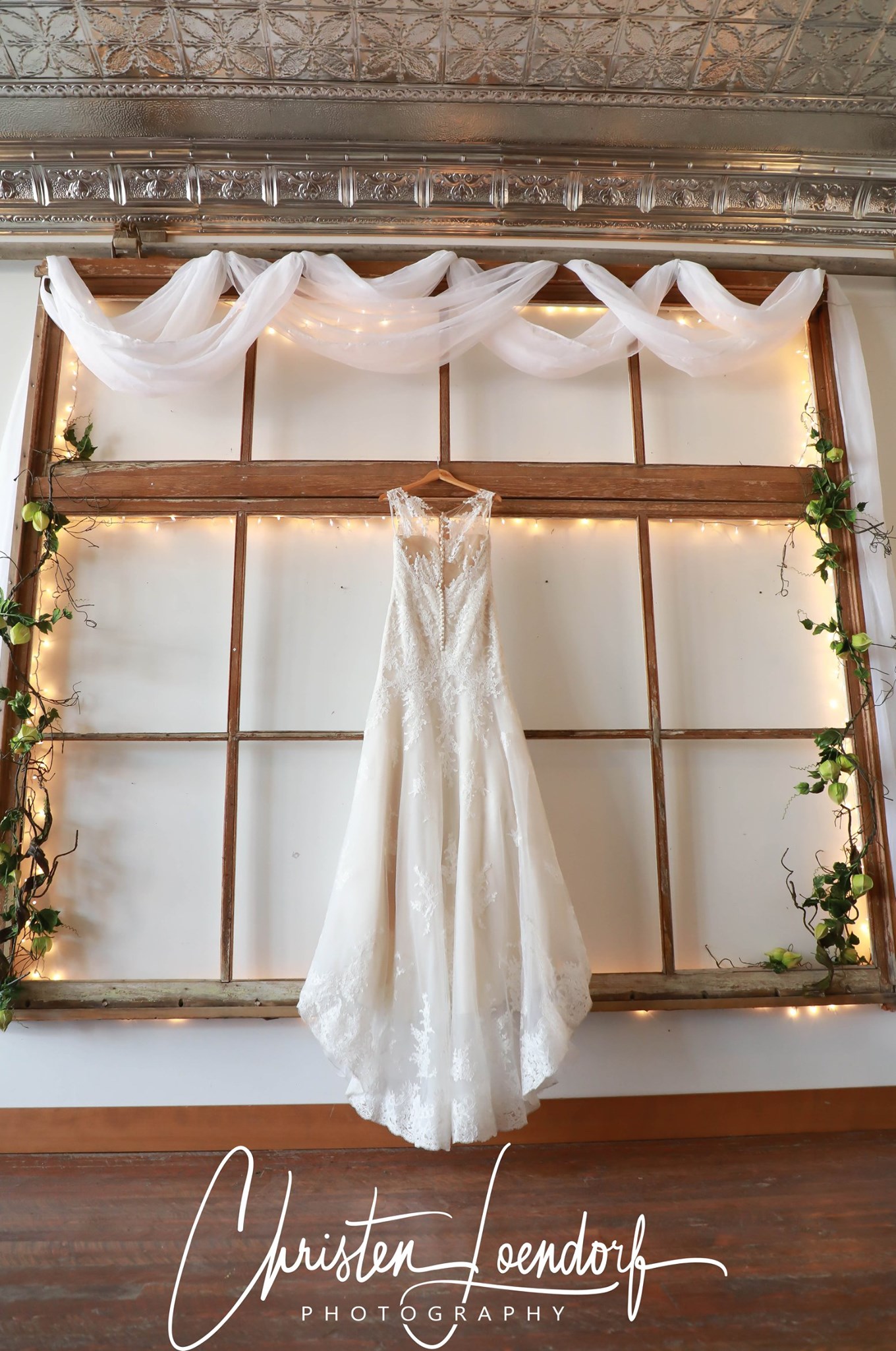 wedding gown hanging in front of large antique window