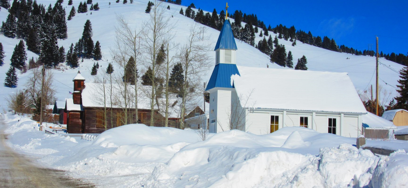snowy church and buildings at base of Montana mountain
